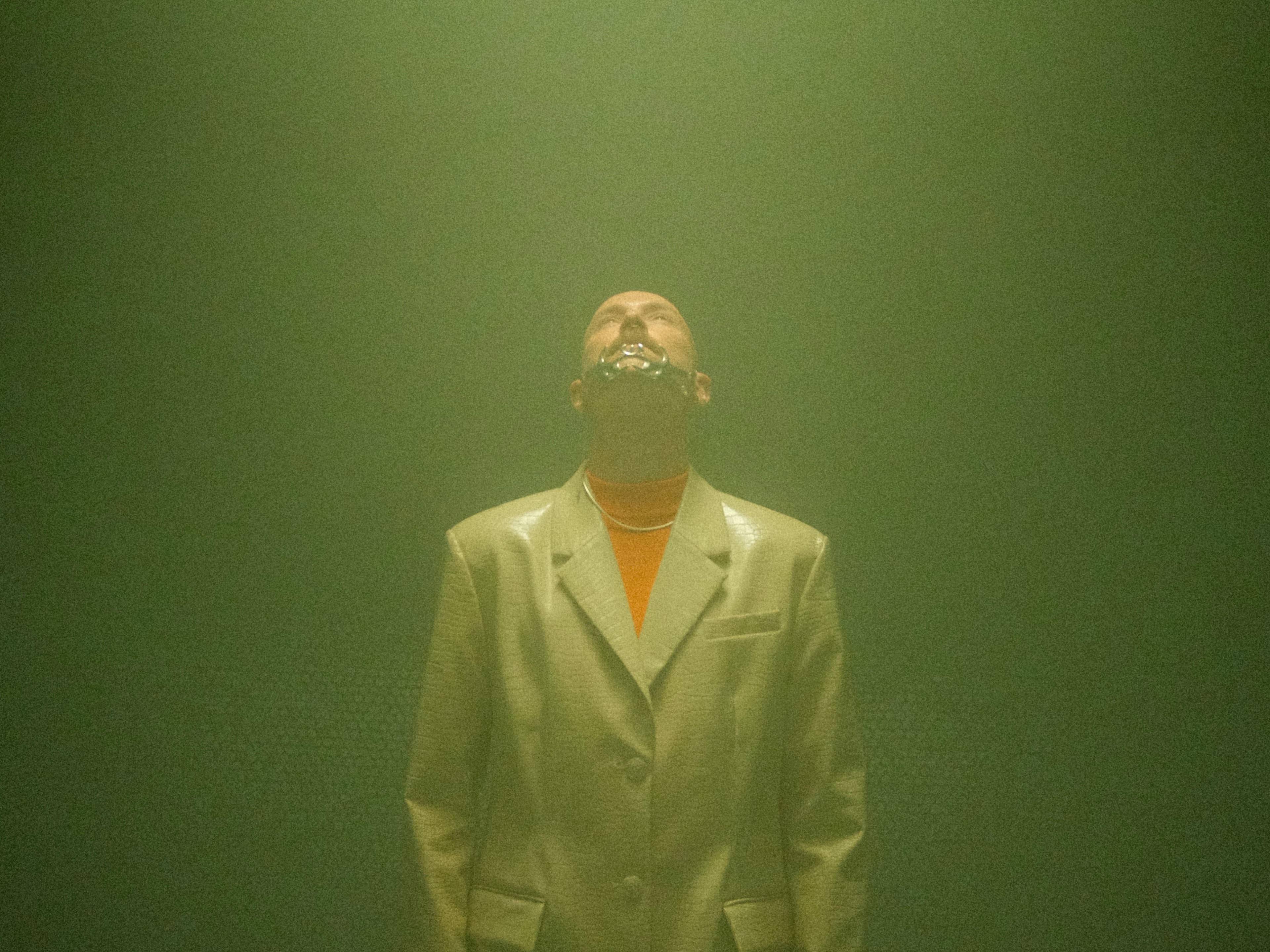 Man in a trenchcoat looking up to a light